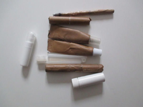 makeup products that have been wrapped in brown packing tape splayed out on a white countertop